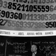 A man in front of a board showing pi in the 1960s.